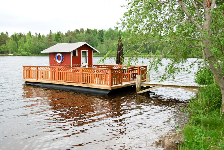 Red sauna hut on dock with deck. A sauna next to a lake is great for cold immersion. Red sauna hut on dock with deck. A sauna next to a lake is great for cold immersion.