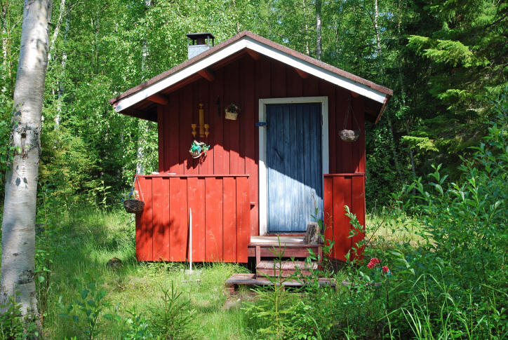 Small traditional red sauna hut with small front deck in the forest. Small traditional red sauna hut with small front deck in the forest.