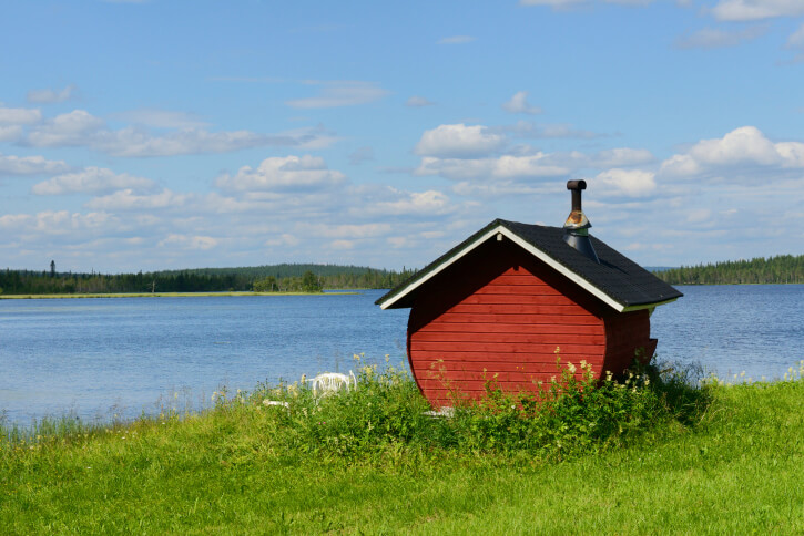 Small red sauna hut built on the edge of a lake Small red sauna hut built on the edge of a lake