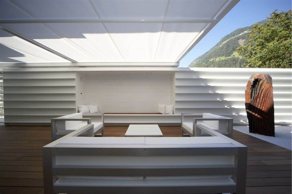 View of outdoors sitting area under retractible sunshade canopy. View of outdoors sitting area under retractible sunshade canopy.