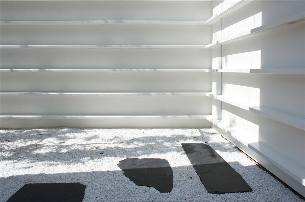 Corner view of garden surrounded by wall with horizontal slats. Corner view of garden surrounded by wall with horizontal slats.