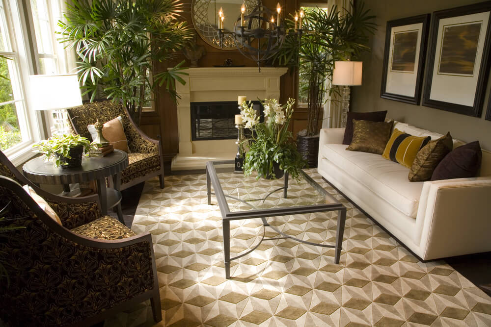 Brown-centric living room design with glass and steel coffee table. Two ornate armchairs with a small round table face a white sofa. Brown-centric living room design with glass and steel coffee table. Two ornate armchairs with a small round table face a white sofa.