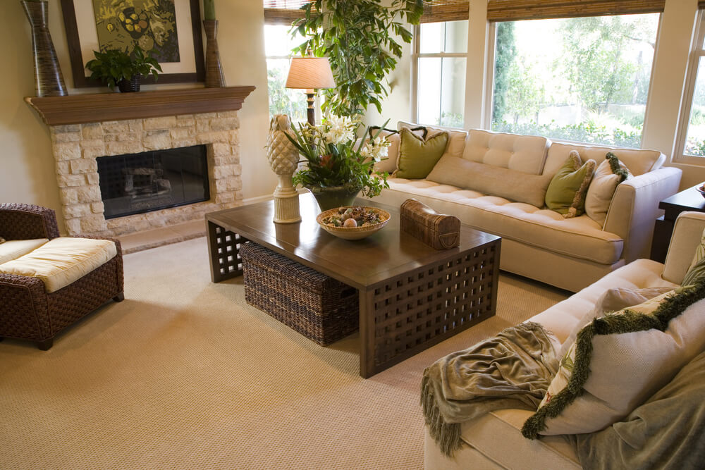 Beige dominant living room design with wood coffee table that has lattice design sides. Room includes dark brown wicker armchair and ottoman. Beige dominant living room design with wood coffee table that has lattice design sides. Room includes dark brown wicker armchair and ottoman.