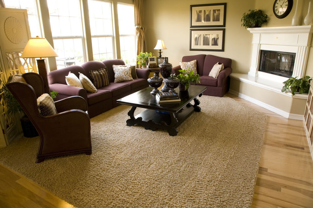 Living room with the fireplace in the corner built in a diagonal formation facing the entire living room made up of matching purple living room furniture. Living room with the fireplace in the corner built in a diagonal formation facing the entire living room made up of matching purple living room furniture.