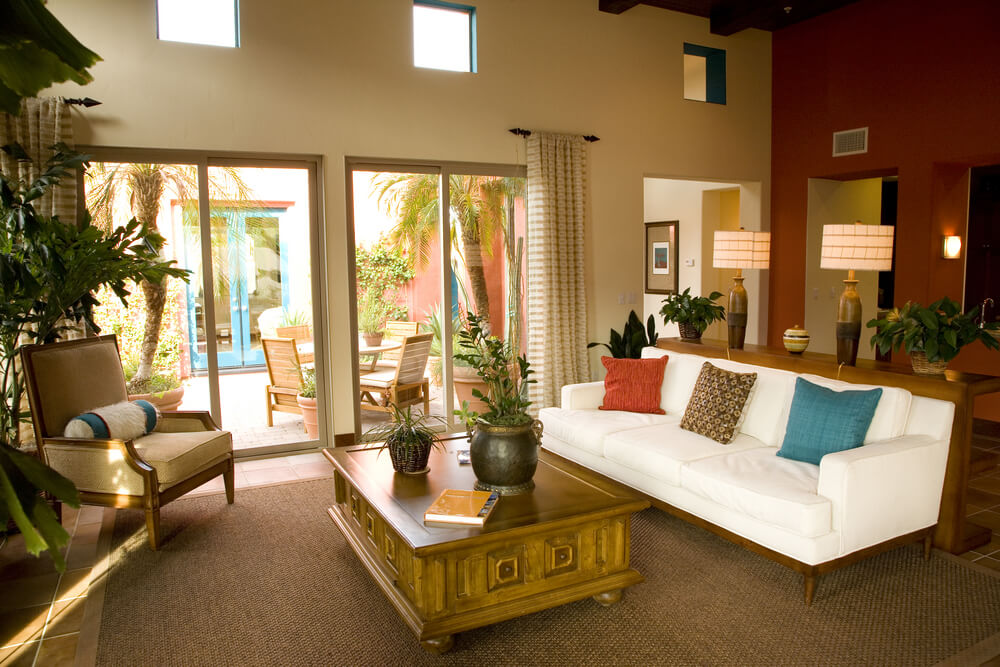 Two-story living room looking out on a courtyard. While it's sparse in decoration, the white sofa with color pillows demonstrates how a white sofa with bright pillows can create a great living room design. Two-story living room looking out on a courtyard. While it's sparse in decoration, the white sofa with color pillows demonstrates how a white sofa with bright pillows can create a great living room design.