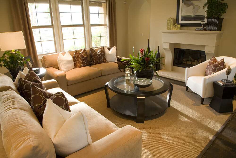 Square living room with a round wood and glass coffee table. Two sofas and one white armchair make up the rest of the furniture along with a small round coffee table in between the two sofas. Square living room with a round wood and glass coffee table. Two sofas and one white armchair make up the rest of the furniture along with a small round coffee table in between the two sofas.