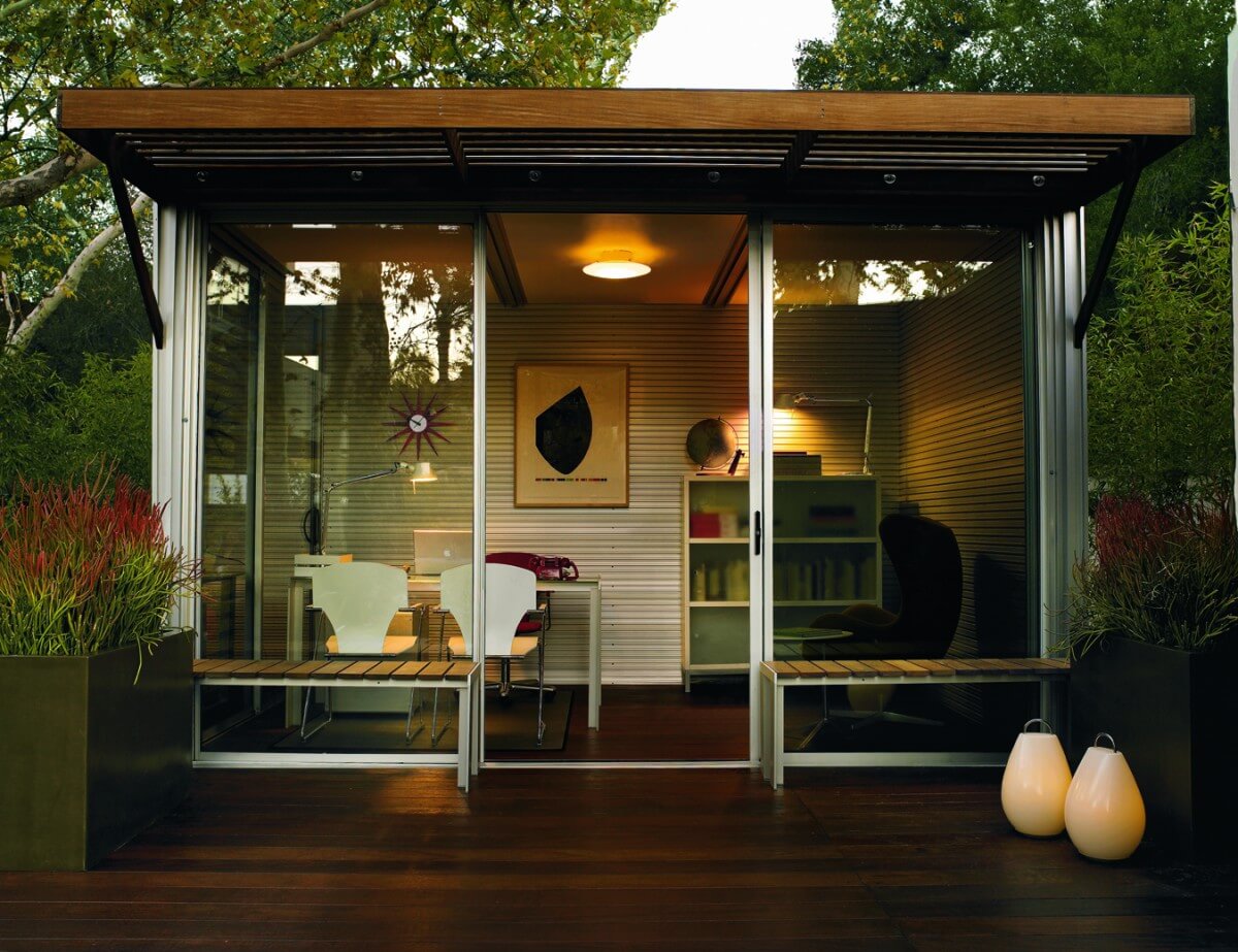 Here is the office module lit up at night, showcasing outdoor seating, and efficient use of space with shelving and easy chair inside. Here is the office module lit up at night, showcasing outdoor seating, and efficient use of space with shelving and easy chair inside.