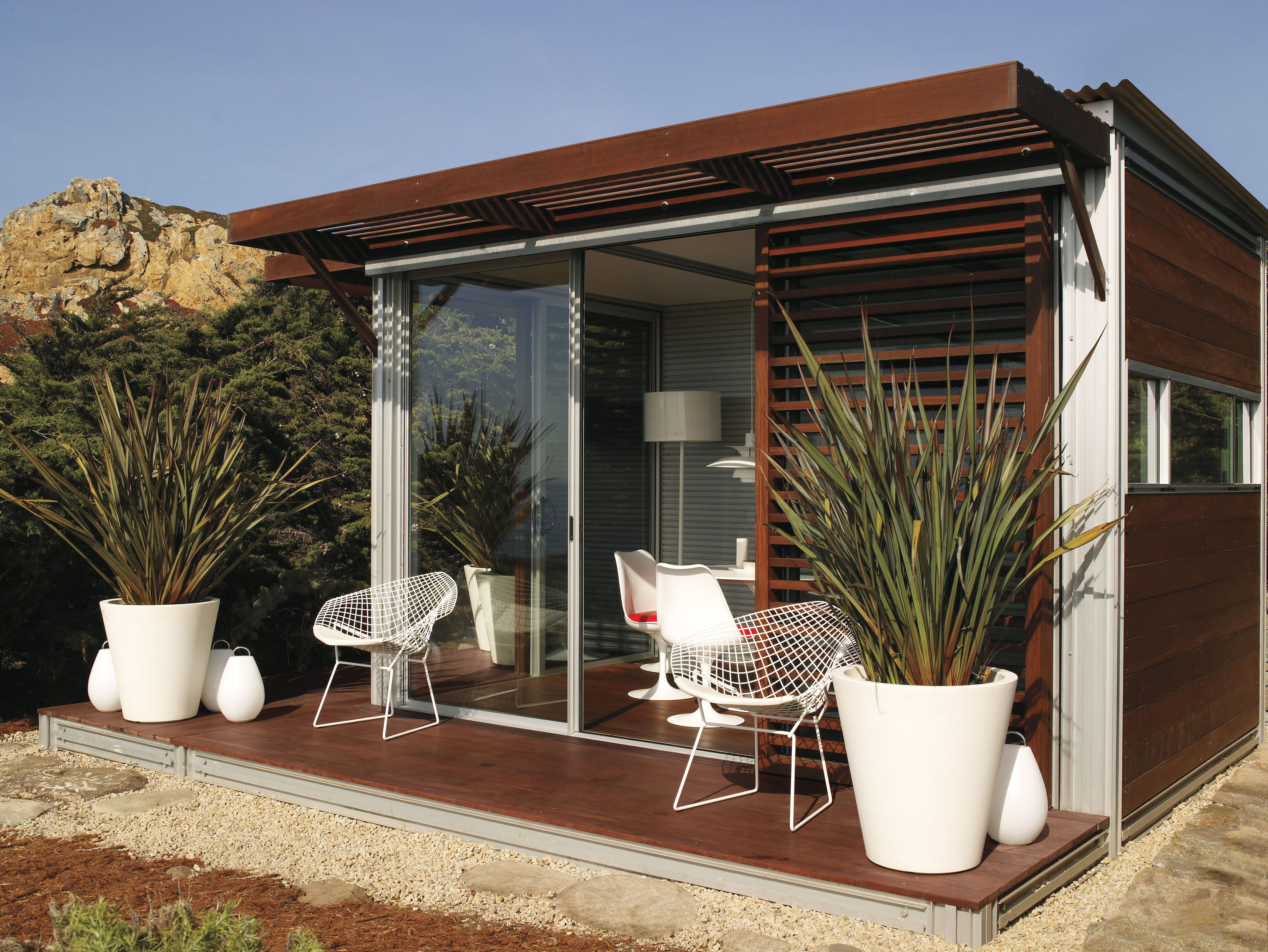KitHaus seen in daylight, with white and red furniture contrasting with natural dark hardwood and floor to ceiling glass. KitHaus seen in daylight, with white and red furniture contrasting with natural dark hardwood and floor to ceiling glass.