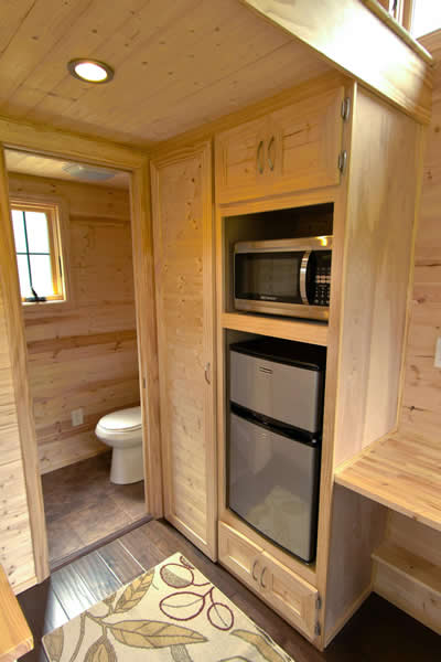 Kitchenette features compact refrigerator and microwave in built-in shelving, with bathroom in background. Kitchenette features compact refrigerator and microwave in built-in shelving, with bathroom in background.