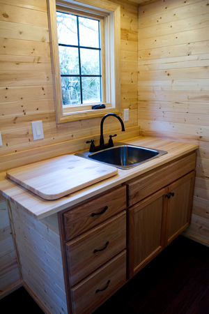 Close up view of kitchen counter with built in cabinetry and cutting board, and full sink. Close up view of kitchen counter with built in cabinetry and cutting board, and full sink.