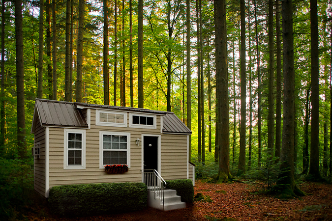 This Tiny Home is painted beige with siding and white window surrounds. Full porch sits at front. This Tiny Home is painted beige with siding and white window surrounds. Full porch sits at front.