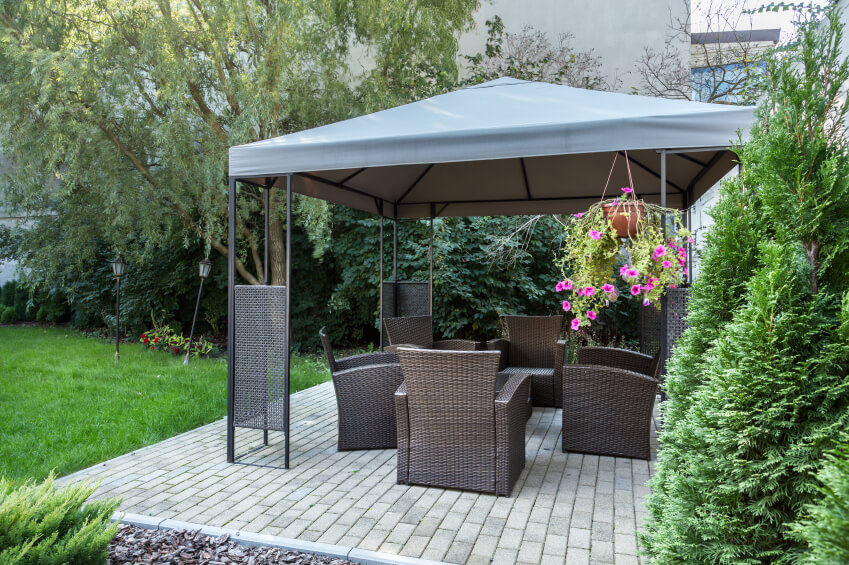 A lovely aluminum gazebo with a canvas canopy. The gazebo is placed over a brick patio and furnished with wicker chairs in a rich chocolate brown. A lovely aluminum gazebo with a canvas canopy. The gazebo is placed over a brick patio and furnished with wicker chairs in a rich chocolate brown.