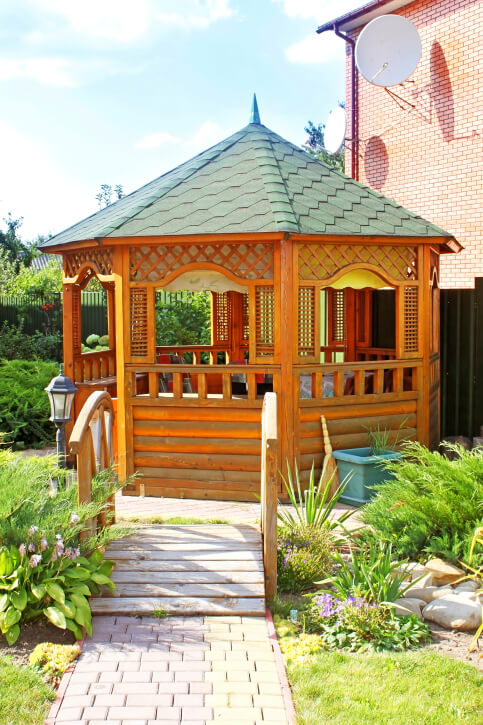The lattice, log-cabin sides, and hexagonal roof shingles give this unique wooden gazebo an exotic look. The lattice, log-cabin sides, and hexagonal roof shingles give this unique wooden gazebo an exotic look.