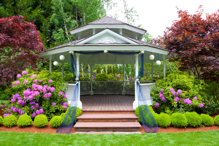 Surrounding your gazebo in large flowering bushes and shrubs creates a secluded retreat. This particular gazebo is enormous and features decorative elements. Surrounding your gazebo in large flowering bushes and shrubs creates a secluded retreat. This particular gazebo is enormous and features decorative elements.