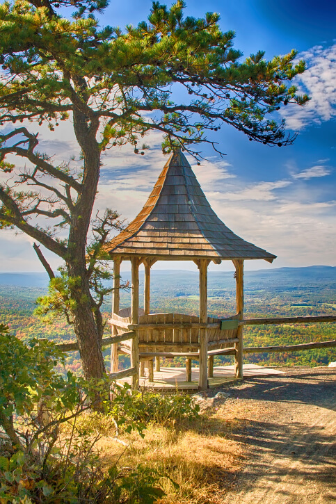 The incredibly tall roof of this small gazebo is shaped somewhat like a witch's hat. It is equipped with rustic benches on four sides. The incredibly tall roof of this small gazebo is shaped somewhat like a witch's hat. It is equipped with rustic benches on four sides.