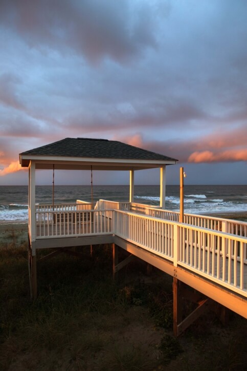 A hard top gazebo at the end of a long walkway over the dunes. The gazebo is equipped with a porch swing that looks out over the waves. A hard top gazebo at the end of a long walkway over the dunes. The gazebo is equipped with a porch swing that looks out over the waves.