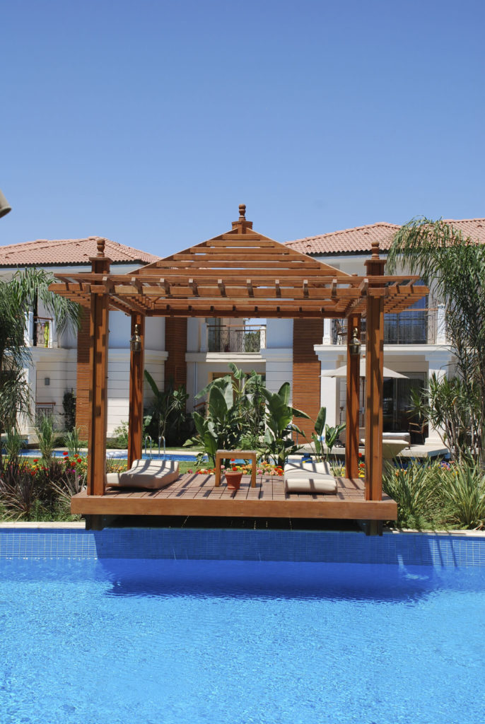 This is a pergola-style gazebo, due to both the open roof and the lattice of bars on the top. The gazebo extends over the side of the pool slightly, making entry easy. This is a pergola-style gazebo, due to both the open roof and the lattice of bars on the top. The gazebo extends over the side of the pool slightly, making entry easy.