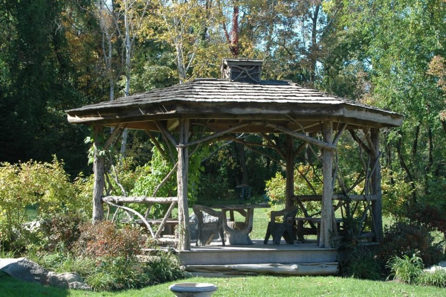 A rustic gazebo made with natural branches and logs. The structure has enough space for a dining area and a relaxation area. A rustic gazebo made with natural branches and logs. The structure has enough space for a dining area and a relaxation area.