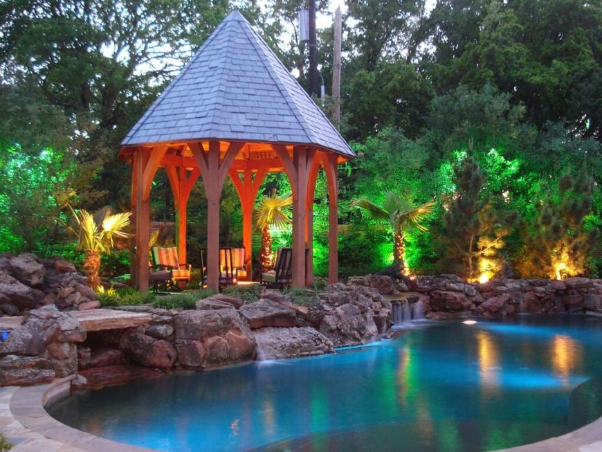 A tall gazebo with a pointed roof, much like a castle turret in fairytales. It sits at the edge of a faux rock waterfall and a pool. A tall gazebo with a pointed roof, much like a castle turret in fairytales. It sits at the edge of a faux rock waterfall and a pool.