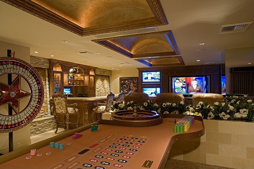 This home features a classy gaming room with a gambling table set along with a living space and a bar area.