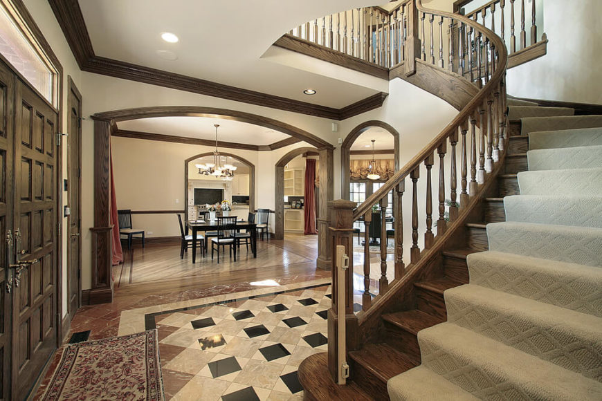 Foyer in older mansion with exposed wood beams, arched wooden staircase with carpet runner. Foyer in older mansion with exposed wood beams, arched wooden staircase with carpet runner.