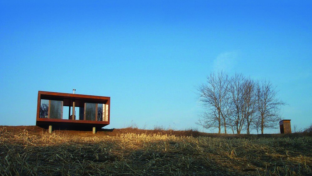 Back view of the Arado house, showcasing its compact design and all glass side overlook. Back view of the Arado house, showcasing its compact design and all glass side overlook.