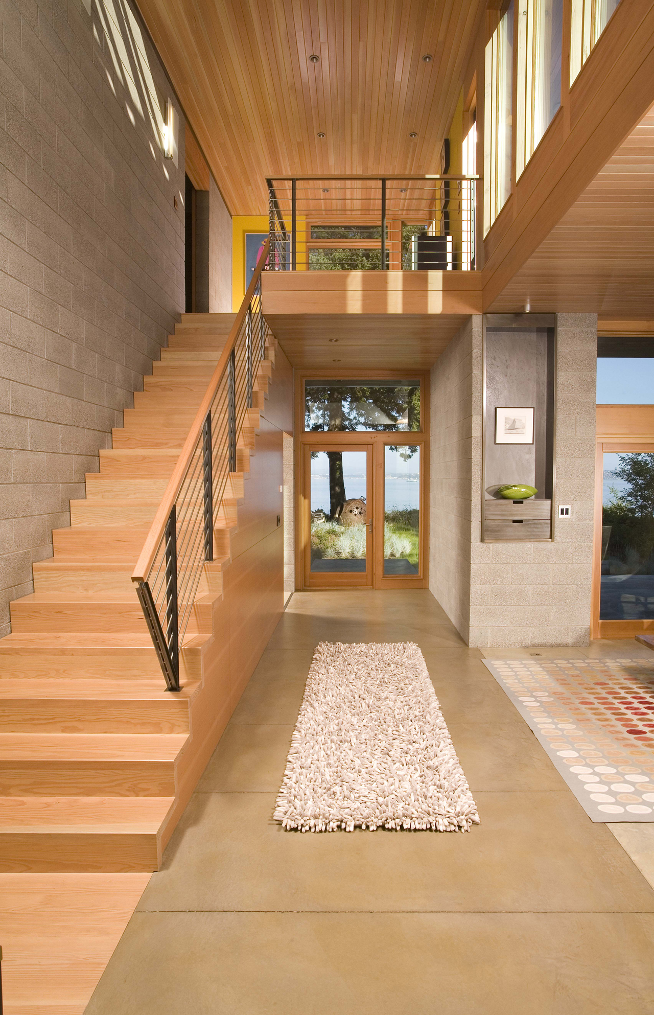 This lovely, warm entryway has a main living area to the right, a staircase to the left, and the short hallway straight ahead leads to the backyard. The entryway is a combination of warm wood and neutral stone tiles. This lovely, warm entryway has a main living area to the right, a staircase to the left, and the short hallway straight ahead leads to the backyard. The entryway is a combination of warm wood and neutral stone tiles.