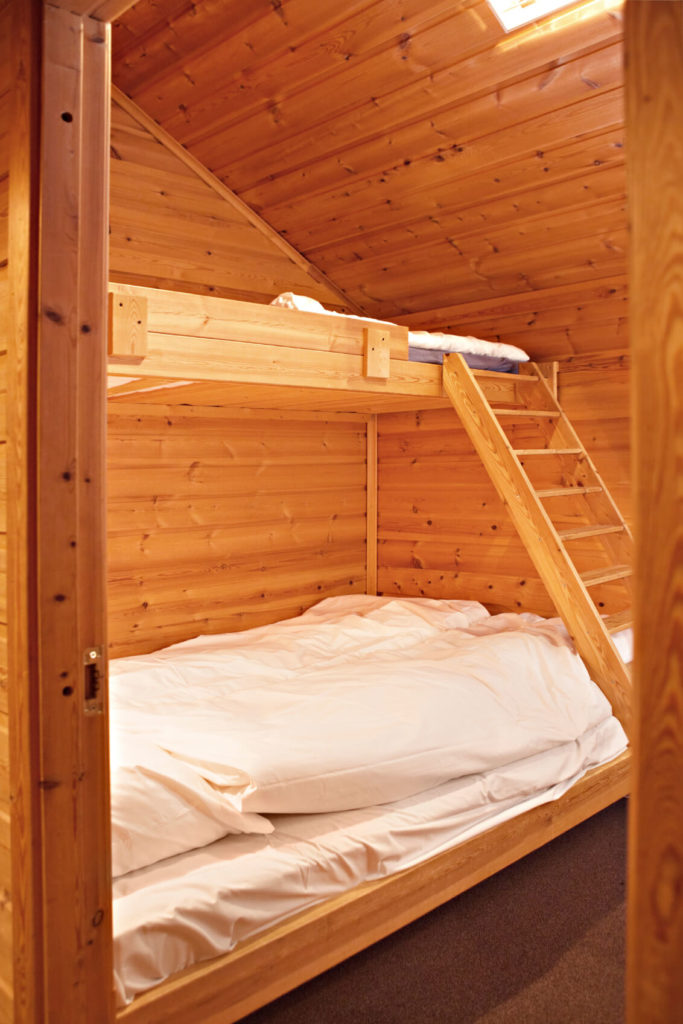 A bedroom constructed of knotty pine creates a rustic backdrop for a bunk bed and simple white bedding to put guests up for a night. A bedroom constructed of knotty pine creates a rustic backdrop for a bunk bed and simple white bedding to put guests up for a night.