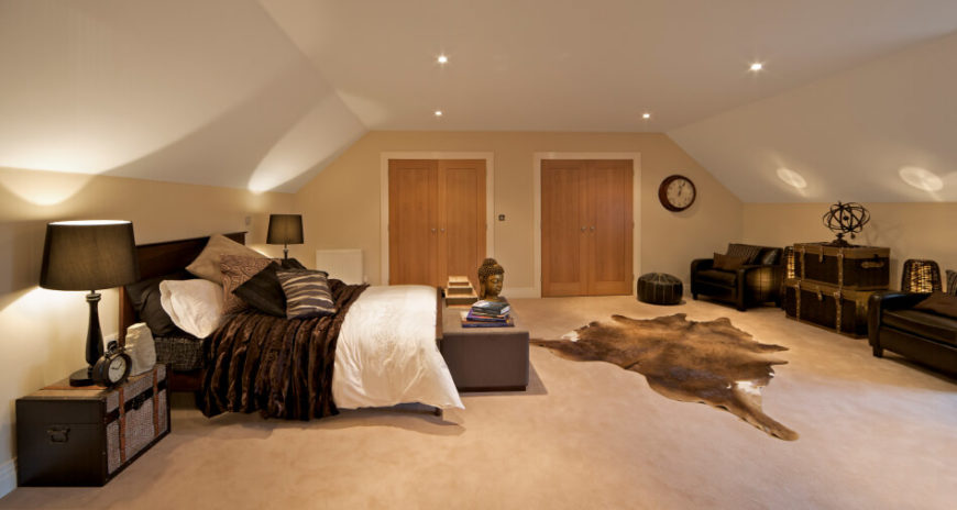 A bedroom that slopes on both sides with a wide center. A pair of double doors lead out of the room. Rich texture and a dark color palette give this space a world-traveller theme. A bedroom that slopes on both sides with a wide center. A pair of double doors lead out of the room. Rich texture and a dark color palette give this space a world-traveller theme.