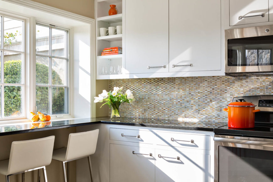  A close up of the eat-in bar facing the window and the beautiful multi-tonal glass backsplash that reaches all the way to the bottom of the wall cabinets. Open shelving on the left is a perfect place to display accents.
