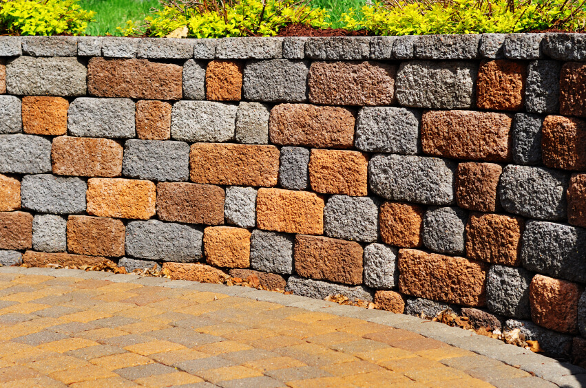 A retaining wall next to a stone courtyard in alternating red and gray stone. A retaining wall next to a stone courtyard in alternating red and gray stone.