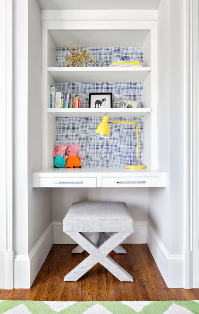 The desk in this children's room has a small upholstered stool that can be swapped out for a larger seat as the child grows. The back of the built-in desk is a blue and white "cheesecloth" pattern that breaks up the neutrals.