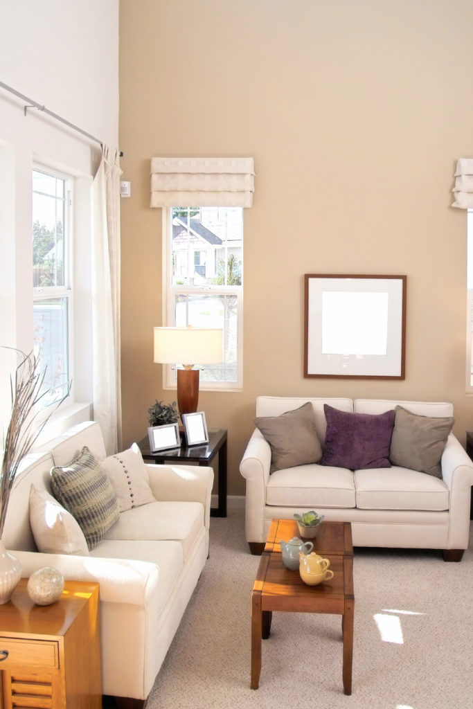 A living room in light taupe and ivory with side tables in varying shades of wood from a dark finish to a more natural oak. The cathedral ceilings help give this small space an open, large feel. A living room in light taupe and ivory with side tables in varying shades of wood from a dark finish to a more natural oak. The cathedral ceilings help give this small space an open, large feel.