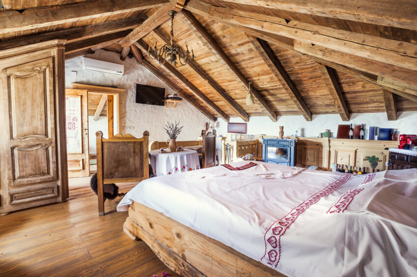A charming shabby-chic bedroom with mismatched wood furniture and delicate linens with embroidery. A charming shabby-chic bedroom with mismatched wood furniture and delicate linens with embroidery.