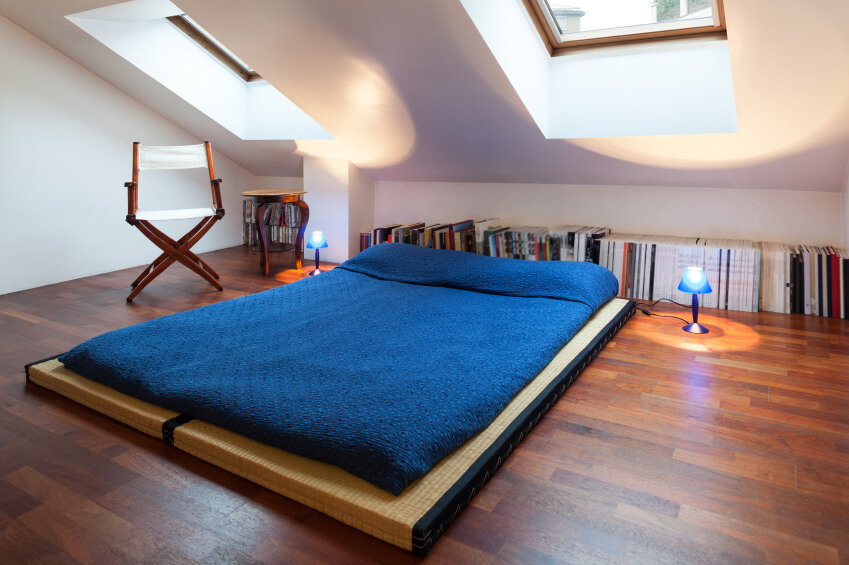 A simple bedroom on a tatami mat and a row of books along the back wall. A simple bedroom on a tatami mat and a row of books along the back wall.