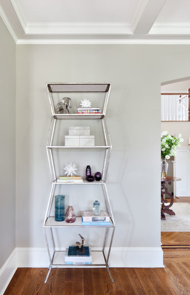  A close up of the modern shelving unit near the entrance to the room, which holds books and other eclectic decorative elements.