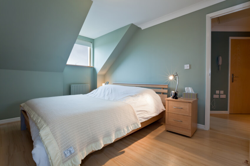 A soft blue wall color is complemented by delicately striped bed linens. A large window gives this otherwise dark space some natural light. A soft blue wall color is complemented by delicately striped bed linens. A large window gives this otherwise dark space some natural light.
