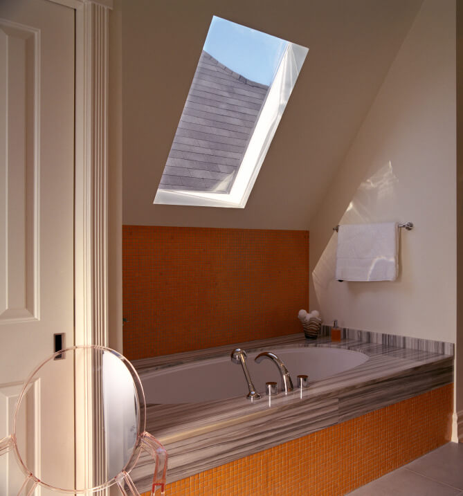 This skylight hovers above a bathtub encased in bold orange petite tiles and topped with exquisitely veined stone work. This skylight hovers above a bathtub encased in bold orange petite tiles and topped with exquisitely veined stone work.