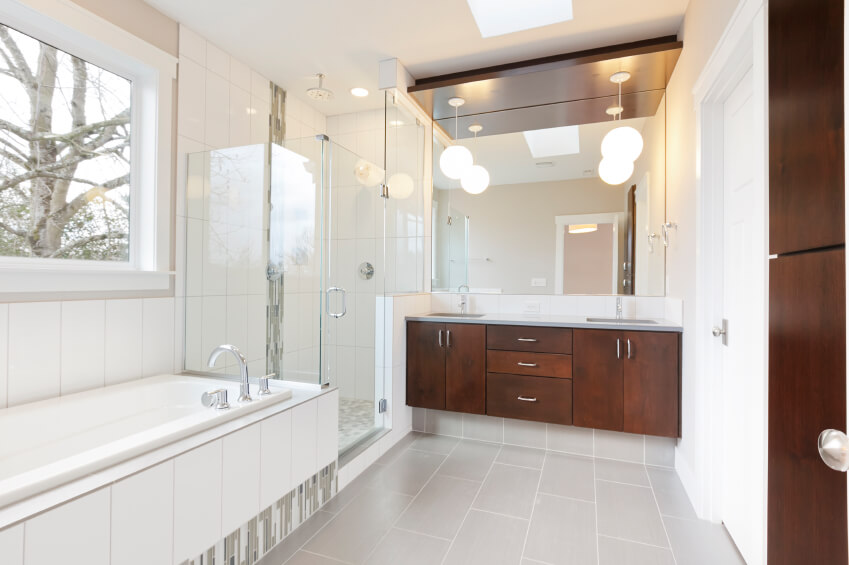 This light bathroom space offers contrast in the rich wood of the double vanity and cabinetry. This light bathroom space offers contrast in the rich wood of the double vanity and cabinetry.