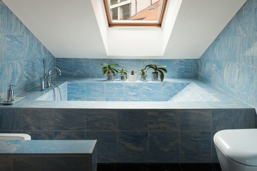 This swirling blue tiling of this impressive bathtub brings to mind a cloudy sky or crashing waves, with either interpretation leading to optimal relaxation. The small wood framed skylight shines just the right amount of light on the space, while decorative plants offer a pop of color as they soak up the sunshine. This swirling blue tiling of this impressive bathtub brings to mind a cloudy sky or crashing waves, with either interpretation leading to optimal relaxation. The small wood framed skylight shines just the right amount of light on the space, while decorative plants offer a pop of color as they soak up the sunshine.