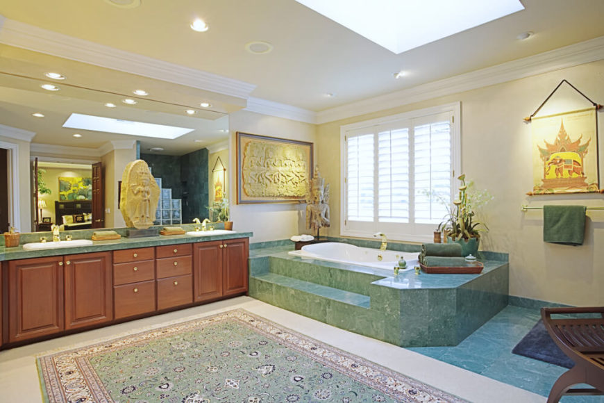 This India inspired bathroom boasts a gorgeous sea-green marbled bathtub casing, seen duplicated in the top of the gorgeous double vanity. A large coordinating area rug sits atop an ivory floor, while a skylight assists in brightening the space. Richly detailed decorations keep with the theme. This India inspired bathroom boasts a gorgeous sea-green marbled bathtub casing, seen duplicated in the top of the gorgeous double vanity. A large coordinating area rug sits atop an ivory floor, while a skylight assists in brightening the space. Richly detailed decorations keep with the theme.