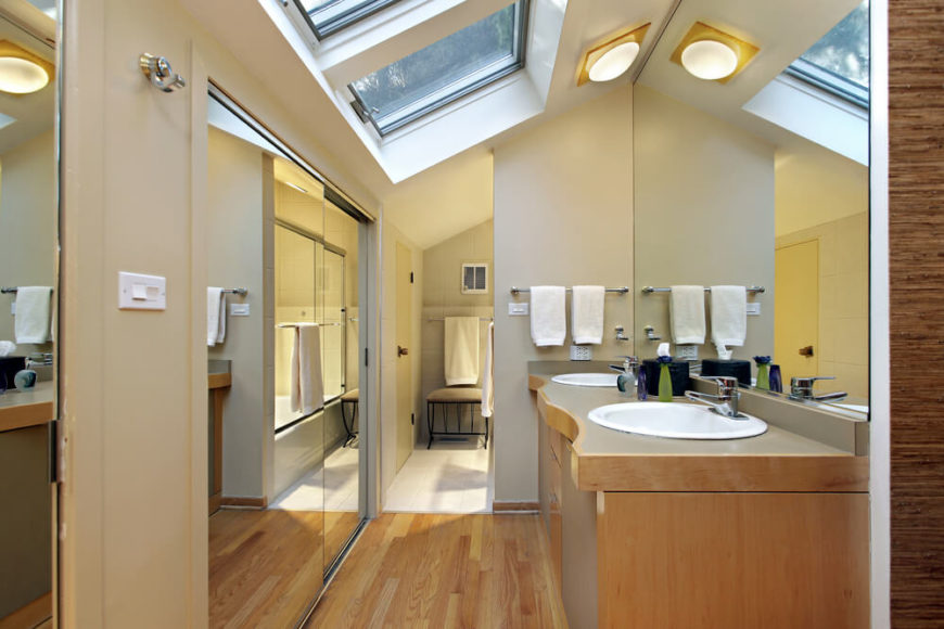 Gorgeous skylights are reflected in the large mirror above the double vanity, maximizing daylight and opening up this small space. Natural hardwood floors lead into the main bathing area, while beige walls offer a neutral backdrop allowing the mirrored walls to take center stage. Gorgeous skylights are reflected in the large mirror above the double vanity, maximizing daylight and opening up this small space. Natural hardwood floors lead into the main bathing area, while beige walls offer a neutral backdrop allowing the mirrored walls to take center stage.