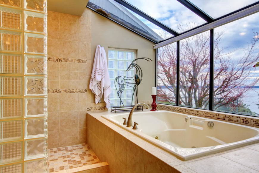 This luxurious bathroom space has a three seasons room feel, with gorgeous views of nature and a large, peaceful lake. The delicate tile-work offers interest in pattern and details, with darker tiles interspersed amongst the lighter pieces. This luxurious bathroom space has a three seasons room feel, with gorgeous views of nature and a large, peaceful lake. The delicate tile-work offers interest in pattern and details, with darker tiles interspersed amongst the lighter pieces.