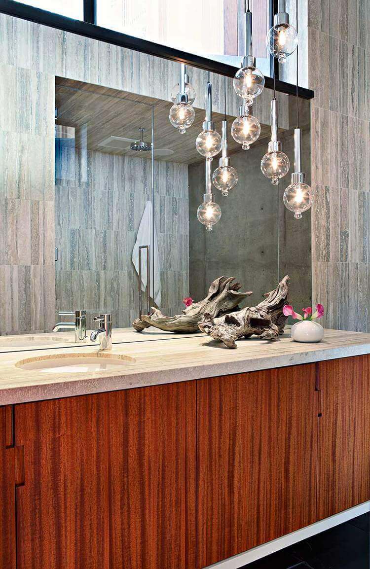 A focused shot at this mid-century primary bathroom's sink counter with a very attractive decoration along with classy pendant lights.