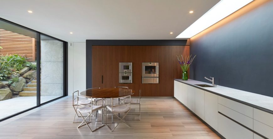 Sleek dining space with a round wooden table paired surrounded by metal chairs over a light hardwood flooring.