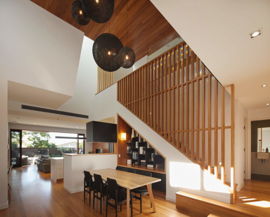 A high ceiling dining space with gorgeous hemp ball chandeliers that hung over the wooden dining table surrounded by black chairs.