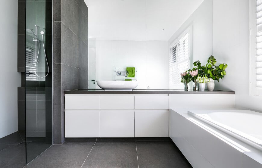 This bathroom has a very minimalist look with a modern color pallet. A large window offers a lot of light to illuminate the glossy white features in this space. This bathroom has a very minimalist look with a modern color pallet. A large window offers a lot of light to illuminate the glossy white features in this space.