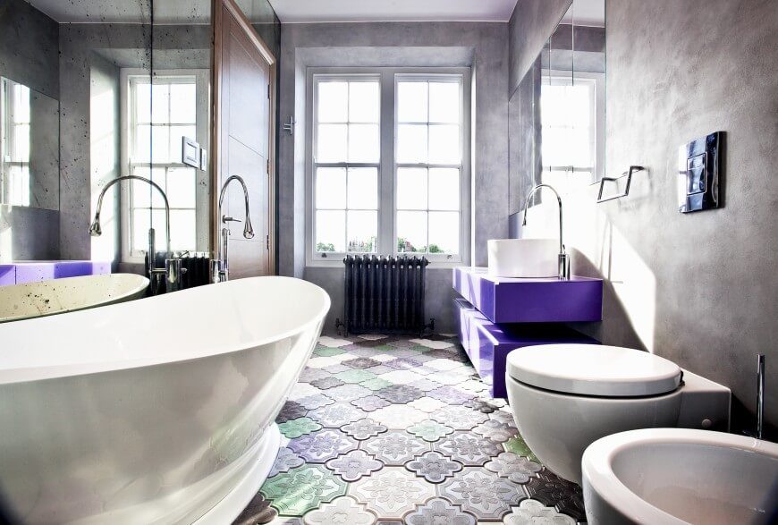 This whimsical bathroom favors the purple color pallet. This space also includes a cylinder shaped vessel sink and a large window for natural lighting. This whimsical bathroom favors the purple color pallet. This space also includes a cylinder shaped vessel sink and a large window for natural lighting.
