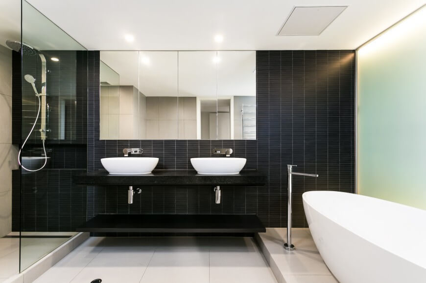 This bathroom has a huge shower head in the glass enclosed shower. A black backsplash gives a fierce color scheme to this exquisite space. This bathroom has a huge shower head in the glass enclosed shower. A black backsplash gives a fierce color scheme to this exquisite space.