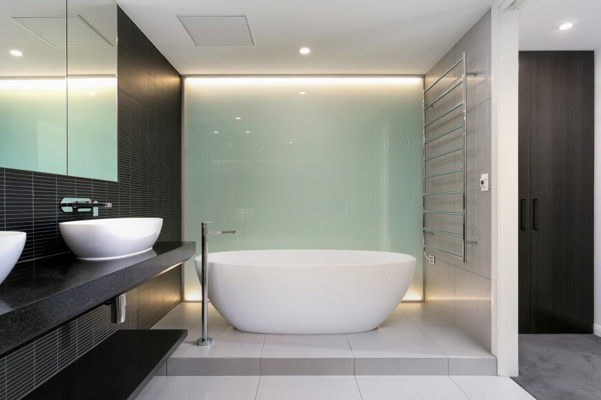 The same bathroom from another angle exposes the modern shape of the bathroom and the frosted glass window beside it. Lights on both the top and the bottom of the glass give it a dazzling glimmer. The same bathroom from another angle exposes the modern shape of the bathroom and the frosted glass window beside it. Lights on both the top and the bottom of the glass give it a dazzling glimmer.